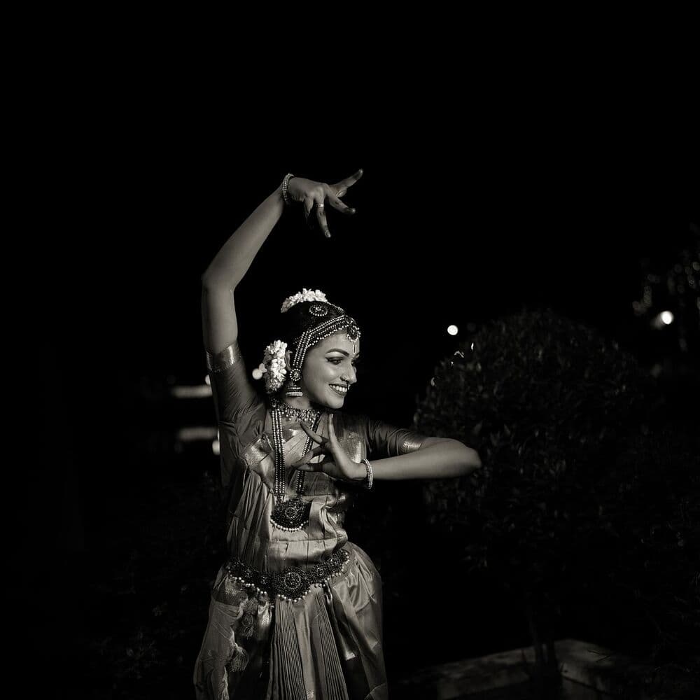 A dancer mid-pose, arm raised, photographed at night