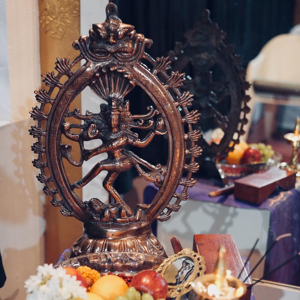 A Nataraja idol with offerings and a lit lamp