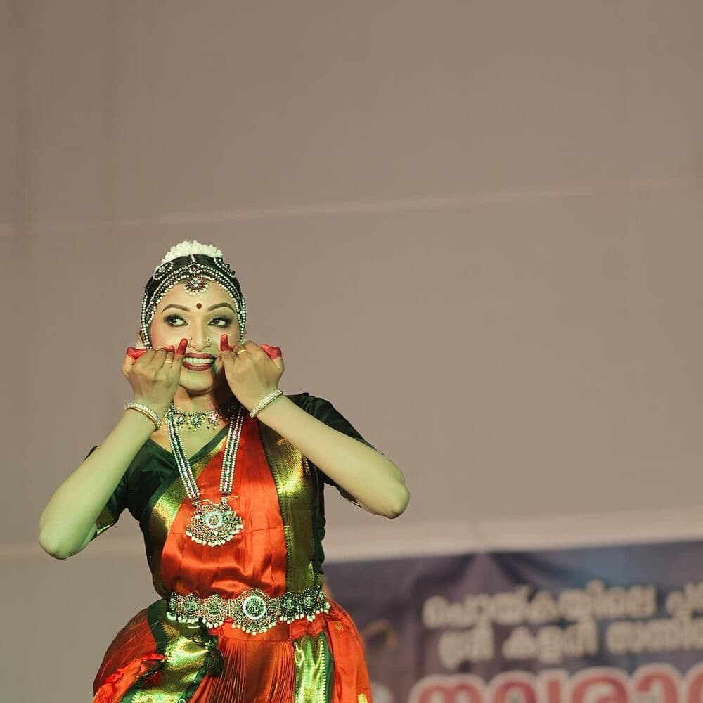 A dancer in close-up, hands framing her face in abhinaya